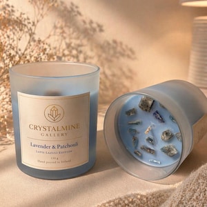 Könnte beinhalten: Eine hellblaue Glaskerze mit dem Text "CRYSTALMINE GALLERY Lavender & Patchouli Lapis Lazuli Edition" und einem Gewicht von 130 g. Die Kerze enthält blaue Steine und wird in Irland von Hand gegossen.