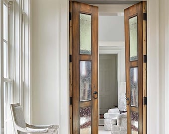 May include: A pair of wooden double doors with frosted glass panels and black door handles. The doors are open and reveal a carpeted room with a white armchair.