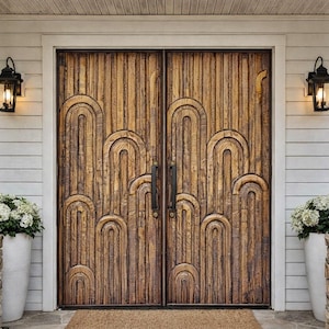 May include: A pair of wooden doors with an arched design. The doors are framed by white siding and stone pillars. Black lanterns flank the doors, and white potted flowers sit on either side.