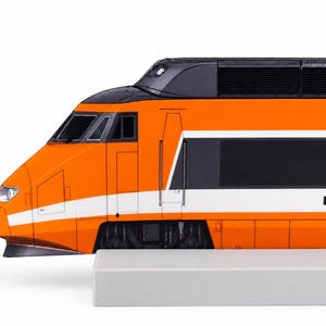 Könnte beinhalten: Eine Modelleisenbahn-Lokomotive mit einem leuchtend orangefarbenen Gehäuse und einem horizontalen weißen Streifen an der Seite. Der obere Bereich ist schwarz mit dunklen Lüftungsgittern, und vorne befinden sich ein Scheinwerfer und dunkle Fenster.