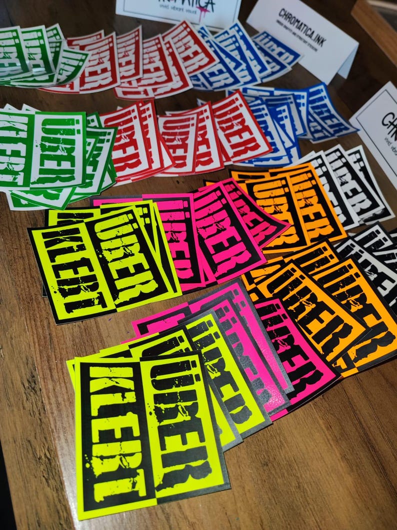 Op de afbeelding: Een verzameling kleurrijke stickers met het woord "VIBERT" in zwart gedrukt op verschillende gekleurde achtergronden, waaronder groen, rood, blauw, oranje, roze en geel.