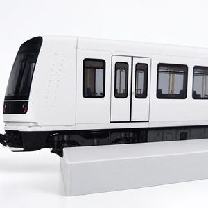 Könnte beinhalten: Ein weißes Modelleisenbahn-Wagenmodell mit schwarzer Frontscheibe, dunkel getönten rechteckigen Fenstern und schwarzem Fahrwerk. Der Wagen ist auf einem weißen rechteckigen Sockel positioniert und zeigt ein schlankes Außendesign mit sichtbaren Türen.