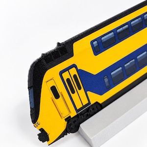 May include: A 3D printed model of a yellow and blue double-decker train car featuring black detailing on the front cab and side windows. The train model is mounted on a rectangular light gray base, showcasing a detailed exterior design.