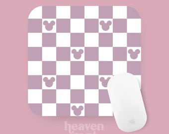 Peut inclure: Un tapis de souris à carreaux violets et blancs avec un motif répété de têtes de Mickey Mouse. Le tapis de souris est sur un fond rose avec une souris blanche dessus. Le texte "heaven sent bakes" est sous le tapis de souris.