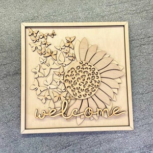 May include: Wooden wall decor featuring a sunflower with a leopard print center surrounded by butterflies and the word "welcome".