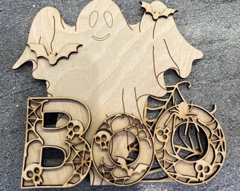 May include: Wooden cutout of a ghost with bats and the word "BOO" in a spooky font with spiderwebs and skulls.