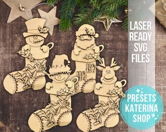 May include: Four laser-cut wooden Christmas stocking ornaments featuring a snowman, Santa Claus, an elf, and a reindeer. Each stocking has a holly sprig and a string of lights.