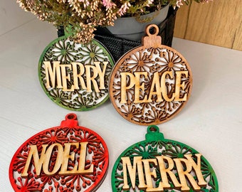 May include: Four wooden Christmas ornaments with a snowflake design. The ornaments are painted in red, green, and natural wood tones. The ornaments have the words "Merry", "Peace", "Noel", and "Merry" written on them.