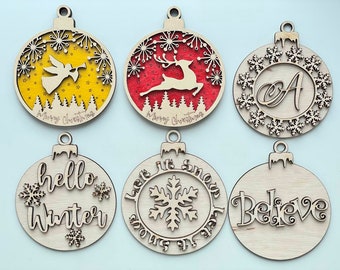 May include: Six wooden Christmas ornaments with various designs. The ornaments are round and have a loop at the top for hanging. The designs include a yellow ornament with an angel and the text "Merry Christmas", a red ornament with a reindeer and the text "Merry Christmas", a natural wood ornament with snowflakes and the text "Let it snow, let it snow, let it snow", a natural wood ornament with the text "hello winter", a natural wood ornament with the text "Believe", and a natural wood ornament with the letter "A" surrounded by snowflakes.