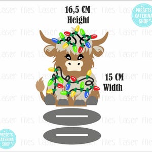 May include: A brown and white Highland cow with a red, green, blue, and yellow string of Christmas lights wrapped around it. The cow is sitting on a gray base with two gray lines. The image includes the text "16.5 CM Height" and "15 CM Width".