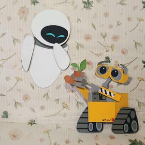 Puede incluir: Recortes bidimensionales de los personajes Eva y Wall-E de la película animada. Eva es blanca con detalles negros y azules. Wall-E es amarillo y gris, sosteniendo una planta en una maceta. El fondo es un estampado floral.