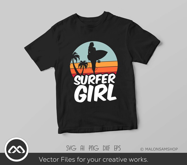 May include: A black t-shirt with a retro-style graphic of a surfer girl standing on a surfboard with palm trees and a sunset in the background. The text "SURFER GIRL" is printed in white below the graphic.