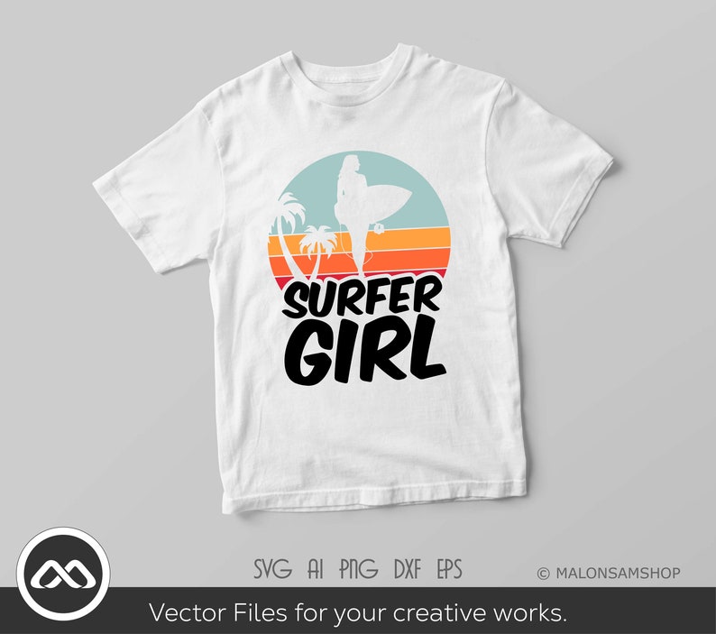 May include: White t-shirt with a retro sunset graphic featuring a silhouette of a surfer girl holding a surfboard. The text "SURFER GIRL" is printed in black below the graphic.