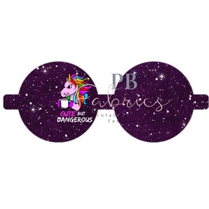 Op de afbeelding: Een paar ronde sublimatie blanks in paars en zwart met een wit glitterontwerp. De linker blank heeft een regenboog unicorn met een koffiebeker en de tekst "Cute But Dangerous". De rechter blank heeft de tekst "PB Fabrics".