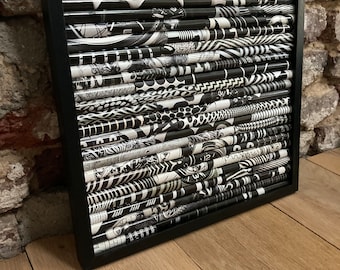 May include: Black and white framed artwork made of rolled paper with various patterns. The artwork is in a black frame and has a modern abstract design.