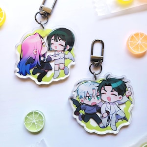 Pode incluir: Dois chaveiros de acrílico com personagens em estilo anime. Um chaveiro mostra dois personagens, um com cabelo rosa e azul e o outro com cabelo verde. O outro chaveiro mostra dois personagens, um com cabelo branco e o outro com cabelo verde.