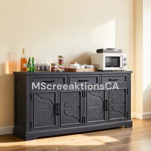 May include: A dark gray wooden sideboard featuring three drawers with black handles and four cabinet doors with decorative paneling. A white microwave, a wooden tray with small white containers, and glass bottles sit on the top surface.
