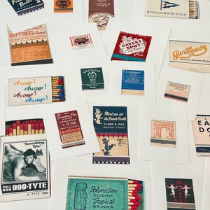 May include: A collection of vintage matchbook cover prints featuring various designs, including Chicago-themed graphics, restaurant advertisements, and retro illustrations. Each print displays unique typography, colorful logos, and iconic imagery from mid-century matchbooks.