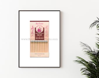 May include: A vintage matchbook cover with a pink and brown design. The text on the cover reads "Ship Tavern" and "Food is King". The matchbook also includes the text "Brown Palace Flowers, Beauty Salon, Barber Shop" and a phone number. The bottom of the matchbook reads "Denver, Colorado 80202".