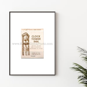 Pode incluir: Uma impressão emoldurada com um design de caixa de fósforos vintage para o Clock Tower Inn. A caixa de fósforos é bege com uma ilustração detalhada de uma torre do relógio e o nome e endereço da estalagem. O texto inclui o número de telefone 815/398-6000.