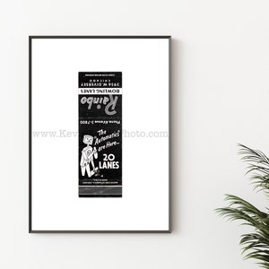 May include: A framed black and white print of a vintage matchbook cover for Rainbo Bowling Lanes. The design features a cartoon robot, the text "The Automatics are Here... 20 LANES", "Phone Avenue 3-7800", and "3956 W. DIVERSEY CHICAGO".