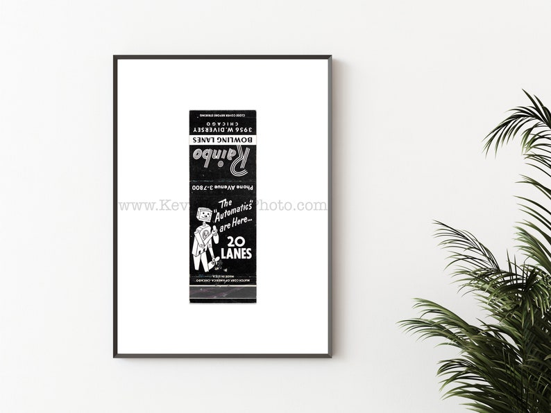 May include: A framed black and white print of a vintage matchbook cover for Rainbo Bowling Lanes. The design features a cartoon robot, the text "The Automatics are Here... 20 LANES", "Phone Avenue 3-7800", and "3956 W. DIVERSEY CHICAGO".