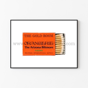 May include: Orange matchbox with the text "The Gold Room, The Arizona Biltmore, Phoenix, Western International Hotels" and a website address. The matchbox is open and contains a row of matches.