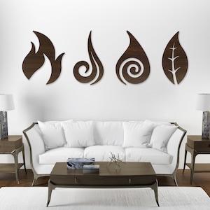 May include: Four wooden wall decor pieces in the shape of a flame, a swirl, a drop of water, and a leaf. The pieces are mounted on a white wall above a white couch in a living room setting.
