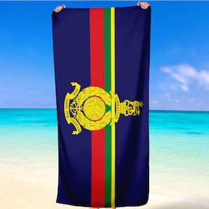 Peut inclure: Une serviette de plage bleue avec une bande rouge, verte et jaune au centre. La serviette présente un blason doré avec les mots "MARE PER TERRAM" et "GIBRALTAR".
