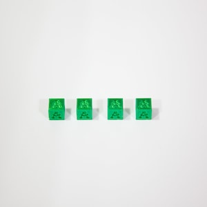 May include: Four green dice with the letter "A" on each side.