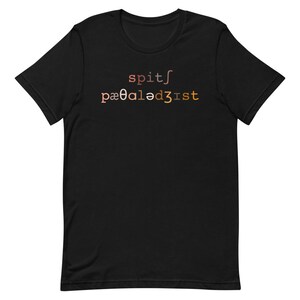 Op de afbeelding: Zwart T-shirt met de tekst "spit/pa00aled3ist" in een verloop van oranje, bruin en roze.