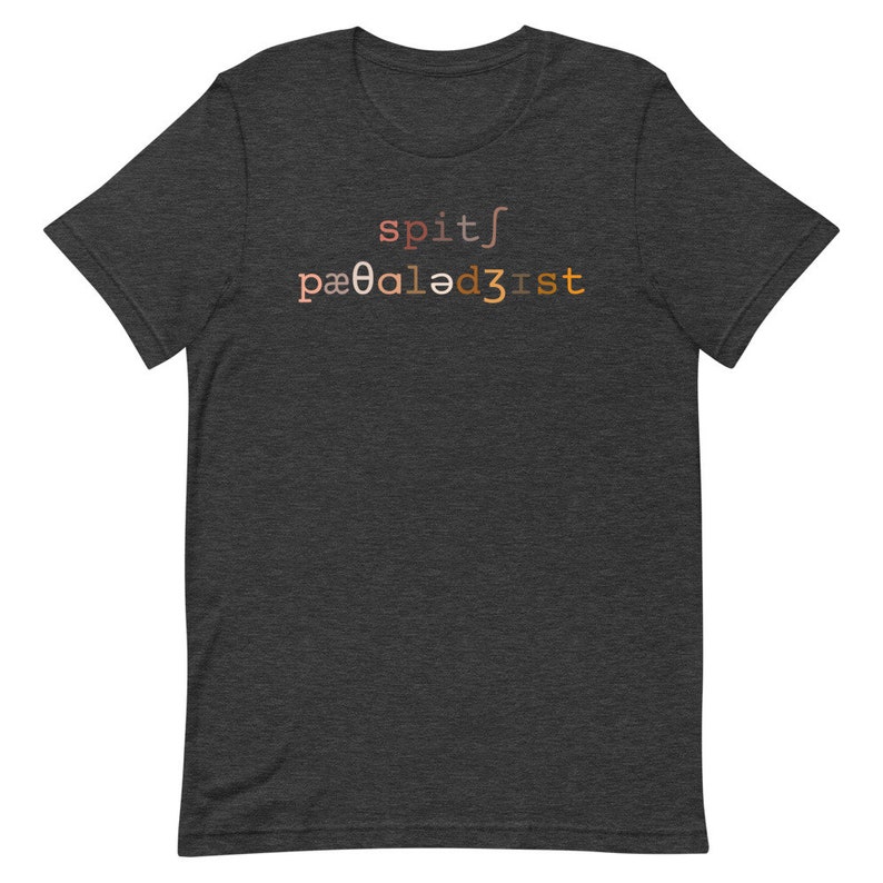 Op de afbeelding: Donker grijs t-shirt met een verloopontwerp dat "spit/pa00aled3ist" luidt.