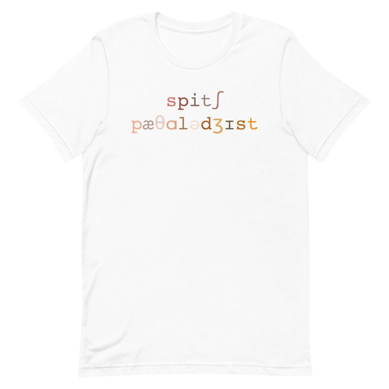 Op de afbeelding: Wit T-shirt met de tekst "spit/pa&infin;al3dist" gedrukt in een verloop van bruin, oranje en geel.