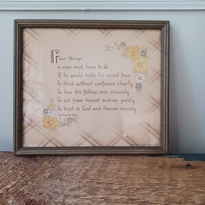 May include: Framed print with a poem by Henry Van Dyke. The text is in a decorative font on a beige background with a diamond pattern. Floral accents in yellow, white, and gray adorn the corners. The frame is a dark brown color.