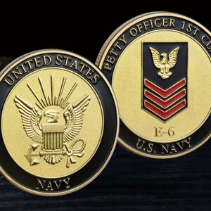 May include: Two gold-colored US Navy challenge coins. One side features the US Navy seal with an eagle and the words "United States Navy". The other side features the words "Petty Officer 1st Class" with a red and gold eagle and the rank insignia, and the words "E-6 U.S. Navy".