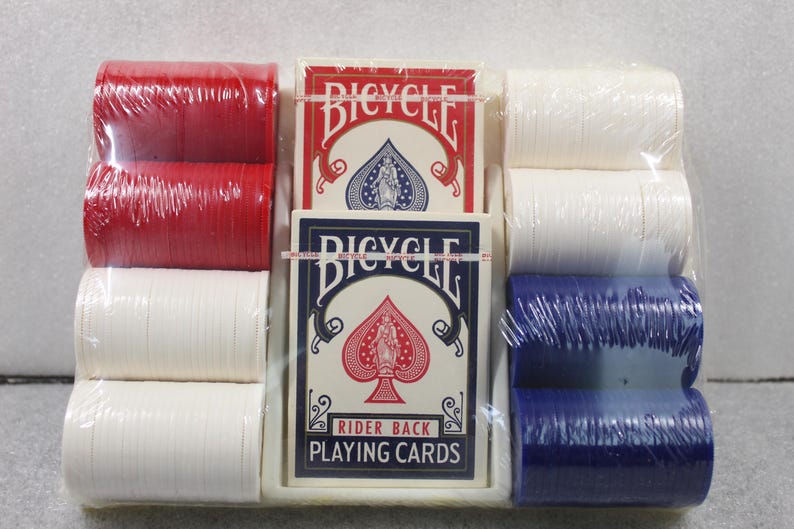 Pu&ograve; includere: Un set confezionato di forniture da poker, tra cui due mazzi di carte da gioco Bicycle Rider Back e pile di fiches da poker rosse, bianche e blu. Le carte sono in una scatola bianca con dettagli rossi e blu.