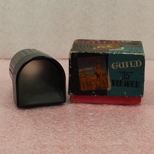May include: A black plastic 35mm slide viewer in its original box. The box is blue and black with the text "Guild "35" Viewer" printed on it.