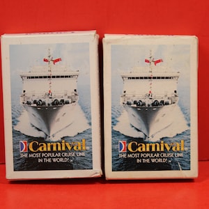 May include: Two white boxes with a picture of a cruise ship on the front. The boxes are labeled "Carnival" and "The Most Popular Cruise Line in the World!"
