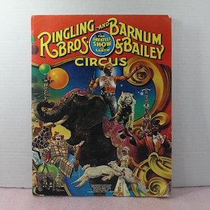 May include: A vintage Ringling Bros. and Barnum & Bailey Circus program featuring a colorful illustration of a circus elephant, a tiger, a clown, and a performer on a trapeze. The text "The Greatest Show on Earth" is visible on the program.