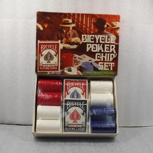 Pu&ograve; includere: Un set di fiches da poker Bicycle in una scatola di cartone. Il set include due mazzi di carte da gioco Bicycle e pile di fiches da poker rosse, bianche e blu. La scatola presenta la scritta "Bicycle Poker Chip Set".