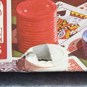 Pu&ograve; includere: Primo piano di un set da poker con fiches rosse e blu, carte da gioco e un mazzo di carte. Le carte mostrano il Re di Picche e il Dieci di Quadri. Il mazzo di carte &egrave; etichettato "BACK CARDS".