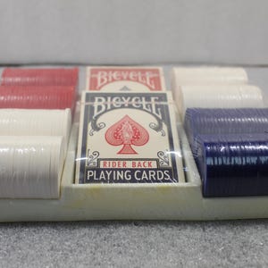 Pu&ograve; includere: Un set di poker confezionato con carte da gioco e pile di fiches da poker rosse, bianche e blu. Le carte da gioco sono del marchio "Bicycle Rider Back Playing Cards". Il set &egrave; in un vassoio di plastica bianco.