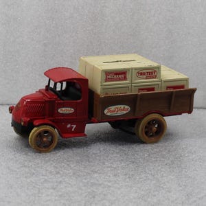 May include: A red vintage toy truck with a brown bed, carrying several cream-colored boxes. The truck has the number 7 on the side and the "True Value" logo. The boxes are labeled "Master Mechanic" and "Tru-Test Paints".