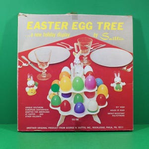 May include: Vintage Easter Egg Tree display box with the text "Easter Egg Tree" and "a new holiday display". The box features a white plastic egg holder with colorful eggs, bunny figurines, and glassware on a red background.