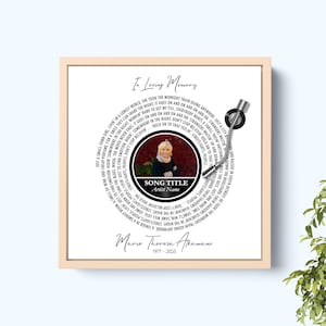 Puede incluir: Impresi&oacute;n enmarcada con un dise&ntilde;o de vinilo, con letras de canciones y una foto. El texto dice "In Loving Memory". La impresi&oacute;n tiene un marco beige y un brazo de disco plateado, ideal para un homenaje.