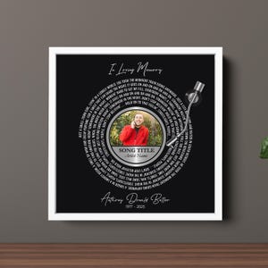 Puede incluir: Una impresi&oacute;n art&iacute;stica conmemorativa enmarcada con un fondo negro, que presenta un dise&ntilde;o circular que se asemeja a un disco de vinilo. El dise&ntilde;o incluye una foto, letras de canciones y el texto "In Loving Memory". Tambi&eacute;n se muestra el nombre y las fechas del artista.