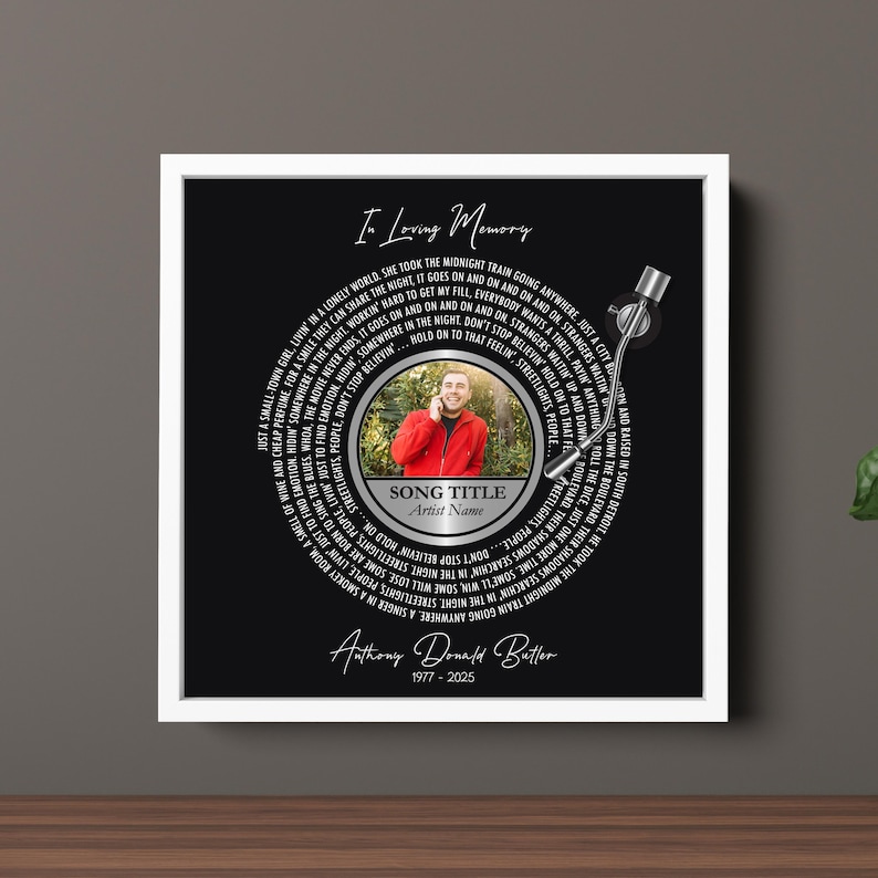 Puede incluir: Una impresi&oacute;n art&iacute;stica conmemorativa enmarcada con un fondo negro, que presenta un dise&ntilde;o circular que se asemeja a un disco de vinilo. El dise&ntilde;o incluye una foto, letras de canciones y el texto "In Loving Memory". Tambi&eacute;n se muestra el nombre y las fechas del artista.