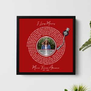 Puede incluir: Una obra de arte enmarcada, roja, con un dise&ntilde;o circular que se asemeja a un disco de vinilo. El texto "In Loving Memory" est&aacute; en la parte superior. El centro incluye una foto y texto para el t&iacute;tulo de una canci&oacute;n y el nombre del artista. La parte inferior tiene un nombre y fechas.
