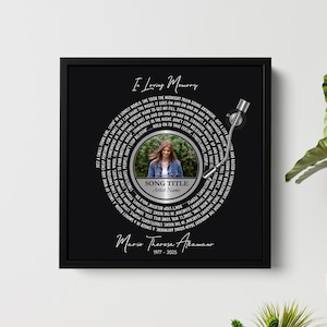 Puede incluir: Una pieza de arte conmemorativa enmarcada en negro con un dise&ntilde;o de disco de vinilo. El centro presenta una foto y texto, incluyendo "Song Title" y "Artist Name". El texto "In Loving Memory" y el nombre "Marie Theresa Akamano" tambi&eacute;n son visibles.