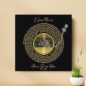 Puede incluir: Impresi&oacute;n en lienzo cuadrada negra con un dise&ntilde;o de tocadiscos vintage. La impresi&oacute;n presenta una foto de un hombre, el texto "In Loving Memory" y letras de canciones. La parte inferior de la impresi&oacute;n tiene el nombre "Anthony Donald Butler" y los a&ntilde;os 1977-2025.
